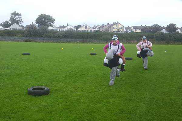Ladies on a Hen Party racing stuffed ostriches on a grass surface.