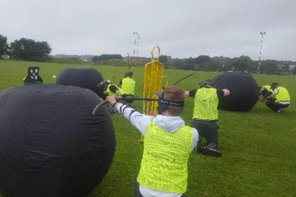 Group of players enjoying Battle Zone Archery on grass surface.